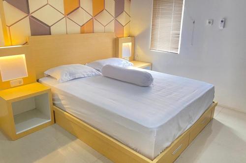 un lit avec des draps blancs et des oreillers dans une chambre dans l'établissement Homestay Syariah Callista Bantaeng Mitra RedDoorz, à Bombong