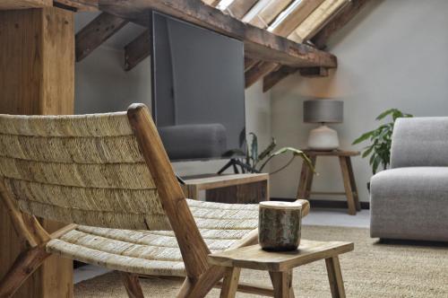 a wooden rocking chair in a living room with a tv at Van Heeckeren Apartments & Suites Buren in Buren