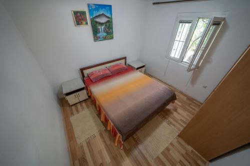 a small bedroom with a bed and a window at Apartments Zeko in Donji Morinj