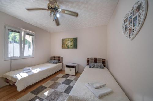 a bedroom with two beds and a ceiling fan at Apartments Zeko in Donji Morinj
