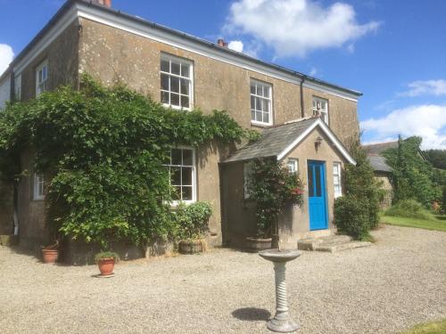 a house with a blue door and a bird bath in front of it at Smeaton Farm Luxury B&B in St. Mellion