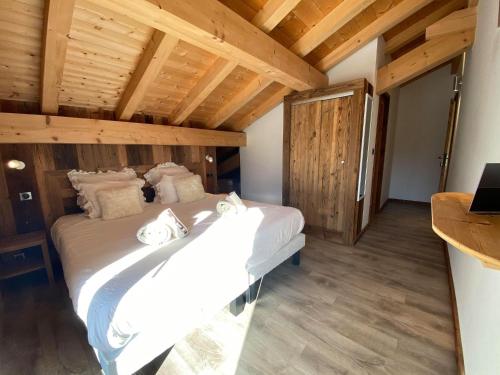 a large white bed in a room with wooden ceilings at Chalet Azalée, Montriond, Morzine, Avoriaz in Montriond
