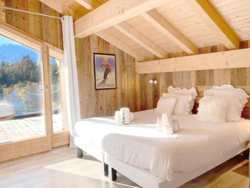 two beds in a room with a large window at Chalet Azalée, Montriond, Morzine, Avoriaz in Montriond