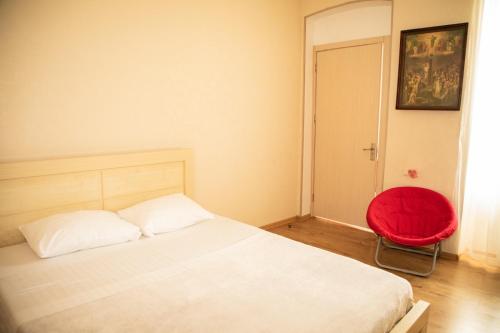 - une chambre avec un lit et une chaise rouge dans l'établissement Natali, à Tbilissi