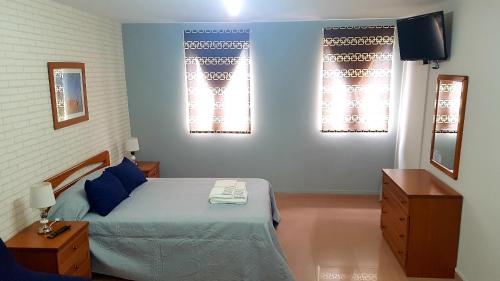 a bedroom with a bed and two windows at Apartamento Loft II Select Real Caldas de Reis in Caldas de Reis