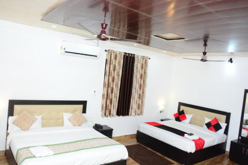 two beds in a room with white walls at HOTEL POLOMAX in Nainital