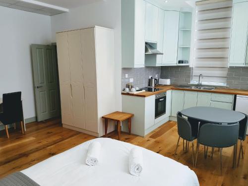 uma cozinha com armários brancos e uma mesa e cadeiras em Forest House Hotel em Londres