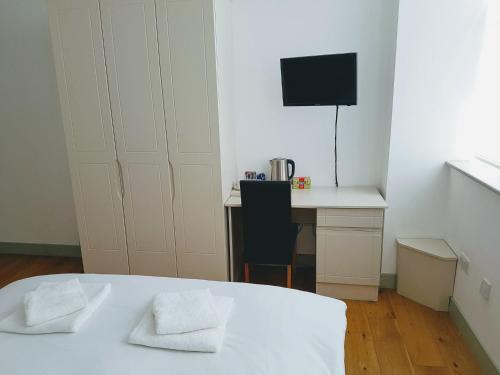 um quarto branco com uma secretária e uma televisão em Forest House Hotel em Londres