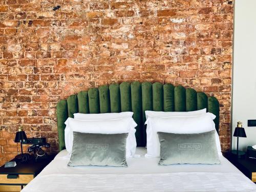 a bed with a green headboard and a brick wall at RUZ Hotels in Istanbul