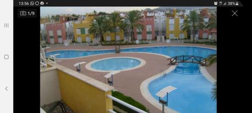 - une vue sur la piscine bordée de palmiers et de bâtiments dans l'établissement Avenida de Juan Sebastián Elcano Apartamento, à Vera