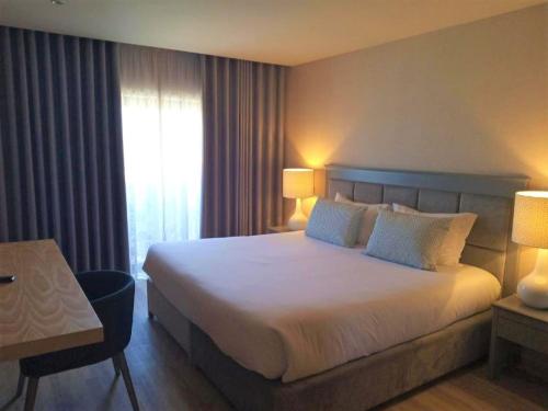 a hotel room with a large bed and a window at Hotel Cristal Vieira Praia & SPA in Praia da Vieira