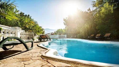 ein Pool mit einer Bank im Hof in der Unterkunft Villa Bonne Maison in Aluschta