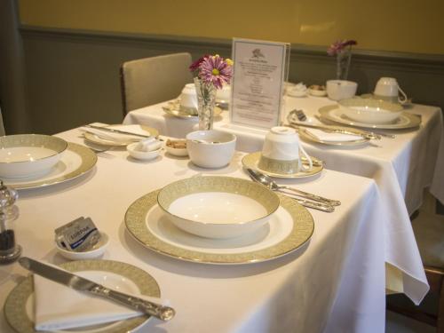 a table with white plates and silverware on it at Albert & Victoria Guest House in Eastbourne