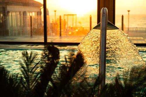 a swimming pool with the sunset in the background at Hotel Cristal Vieira Praia & SPA in Praia da Vieira