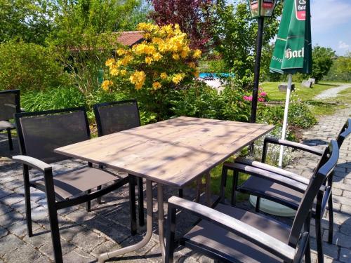 a wooden table with chairs and a green umbrella at Schätzlhof OHG in Ruderting