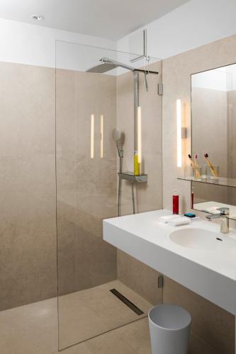 a bathroom with a sink and a glass shower at The Mandala Suites in Berlin