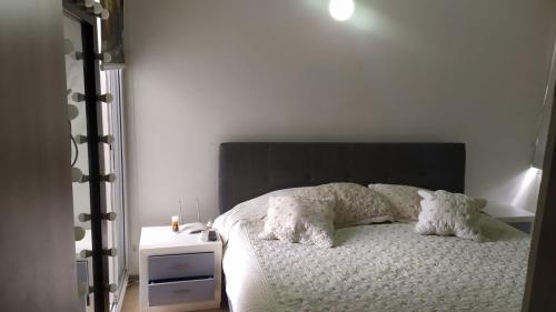 Schlafzimmer mit einem Bett mit einem schwarzen Kopfteil und Kissen in der Unterkunft Excelente apartamento en villeta cundinamarca in Villeta