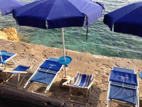 a group of chairs and an umbrella on the beach at Hotel Villa Ombrosa in Portoferraio