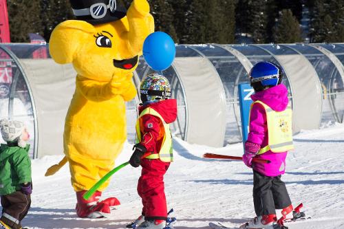 a group of children standing in the snow with mascots at Isskogel Suites in Gerlos