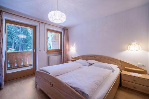 ein Schlafzimmer mit einem großen Bett mit weißer Bettwäsche und einem Fenster in der Unterkunft Ferienhaus Maria Arnika in Pfelders