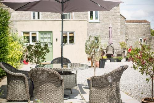 uma mesa e cadeiras com um guarda-sol num pátio em Withy Cottages em Langport