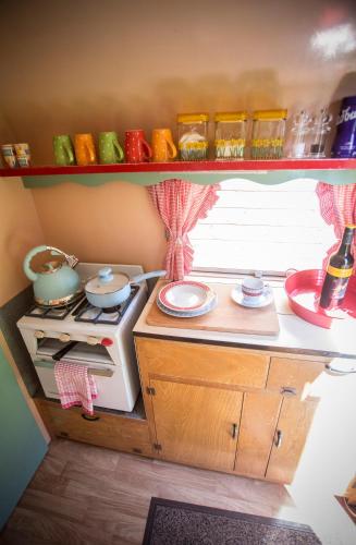 a kitchen with a stove and a shelf with dishes at Withy Cottages in Langport