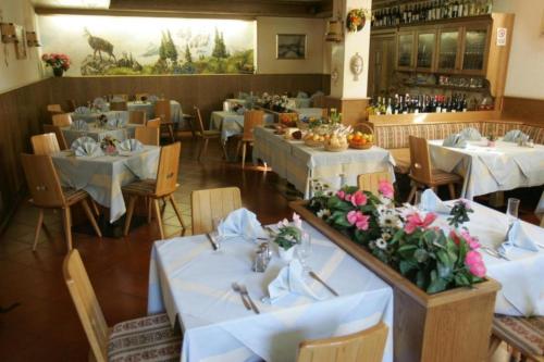 ヴァルディデントロにあるHotel Gardeniaの白いテーブルと花の飾られたレストラン