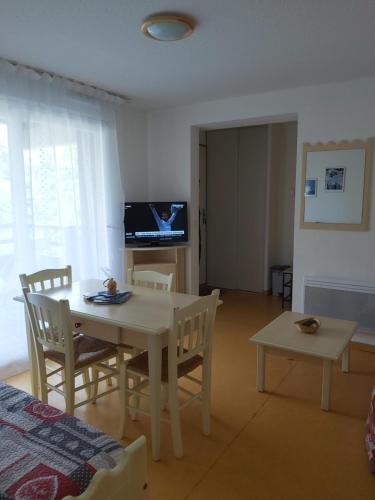 sala de estar con mesa, sillas y TV en Chalet gentiane 1700 en Puy-Saint-Vincent