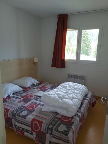a bedroom with a bed with a quilt and a window at Chalet gentiane 1700 in Puy-Saint-Vincent