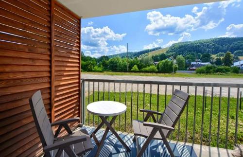 une terrasse avec 2 chaises, une table et une clôture dans l'établissement Apartament Agatka, à Ustrzyki Dolne