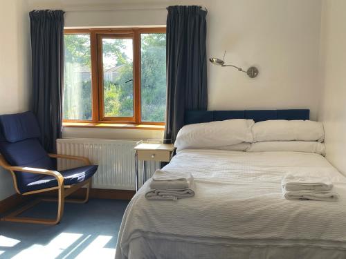 a bedroom with a bed and a chair and a window at O'Domhnaill's Guesthouse - Lig do Scíth in Galway