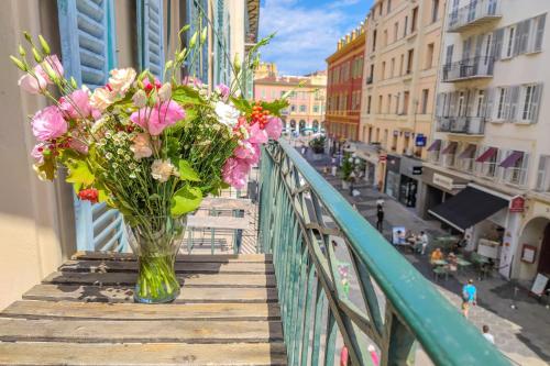 a vase filled with flowers sitting on a balcony at Aparthotel AMMI Nice Massena - ex Ajoupa in Nice
