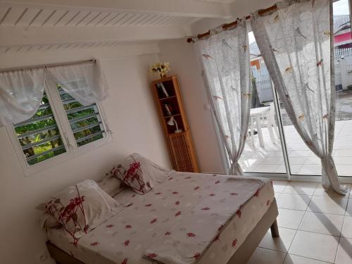 a bed in a room with windows and a bed with a bed frame at Le studio de Jeannine in Capesterre-Belle-Eau