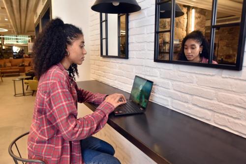 a woman sitting at a counter using a laptop at LATROUPE La Granja in Bilbao