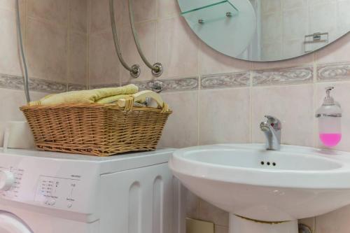 a bathroom with a sink and a basket on a washing machine at Old town Beauty Apartment with great view in Podgorica