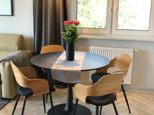 a table and chairs with a vase of flowers on it at Apartamenty Szafirowa Mierzeja - 365PAM in Mielno