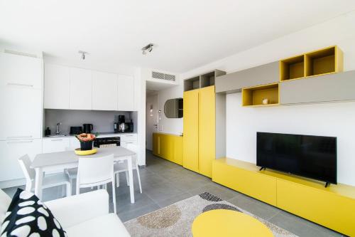 cocina con armarios amarillos y mesa con TV en Flat Iron Apartments by Quokka 360 - modern building 5 min from the centre of Lugano, en Viganello