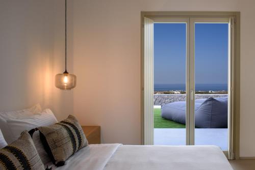 a bedroom with a bed and a sliding glass door at Este Luxury Suites in Fira