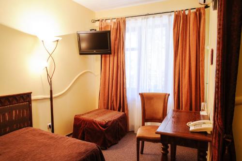 a hotel room with a bed and a desk and a window at Трипільське Сонце in Podgortsy