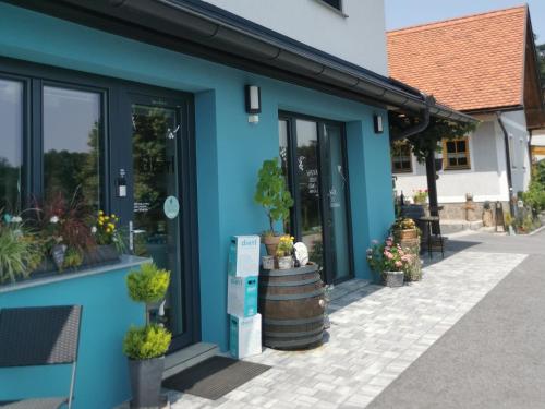 a blue building with a barrel and potted plants at Weingut Dietl in Riegersburg
