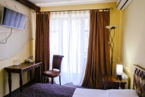 a hotel room with a bed and a desk and a window at Трипільське Сонце in Podgortsy