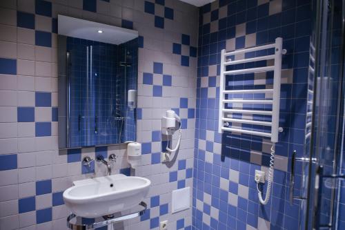 y baño de azulejos azules con lavabo y ducha. en Трипільське Сонце, en Podgortsy