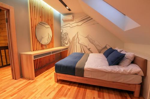 a bedroom with a bed with a mountain mural on the wall at Трипільське Сонце in Podgortsy