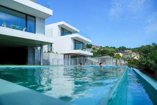 two children swimming in a swimming pool next to a house at Acíes Apartamentos Turísticos in Cangas de Morrazo