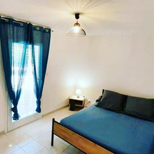 a bedroom with a blue bed and a window at Gite Libecciu in Pietracorbara