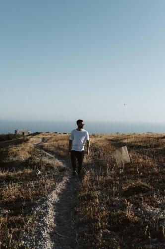 a man walking down a dirt road in a field at Santorini Sky, The Lodge in Pirgos