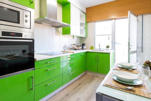 a green kitchen with white and green cabinets at Adeinés Viviendas uso turístico in A Estrada