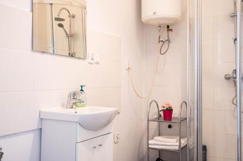 biała łazienka z umywalką i prysznicem w obiekcie Studio Kościuszki w Łodzi