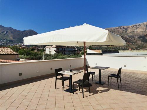 a table and chairs under an umbrella on a roof at Le Métro in Carini