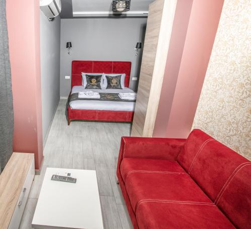 a red couch and a bed in a room at Hotel Sonoma in Kosovo Polje